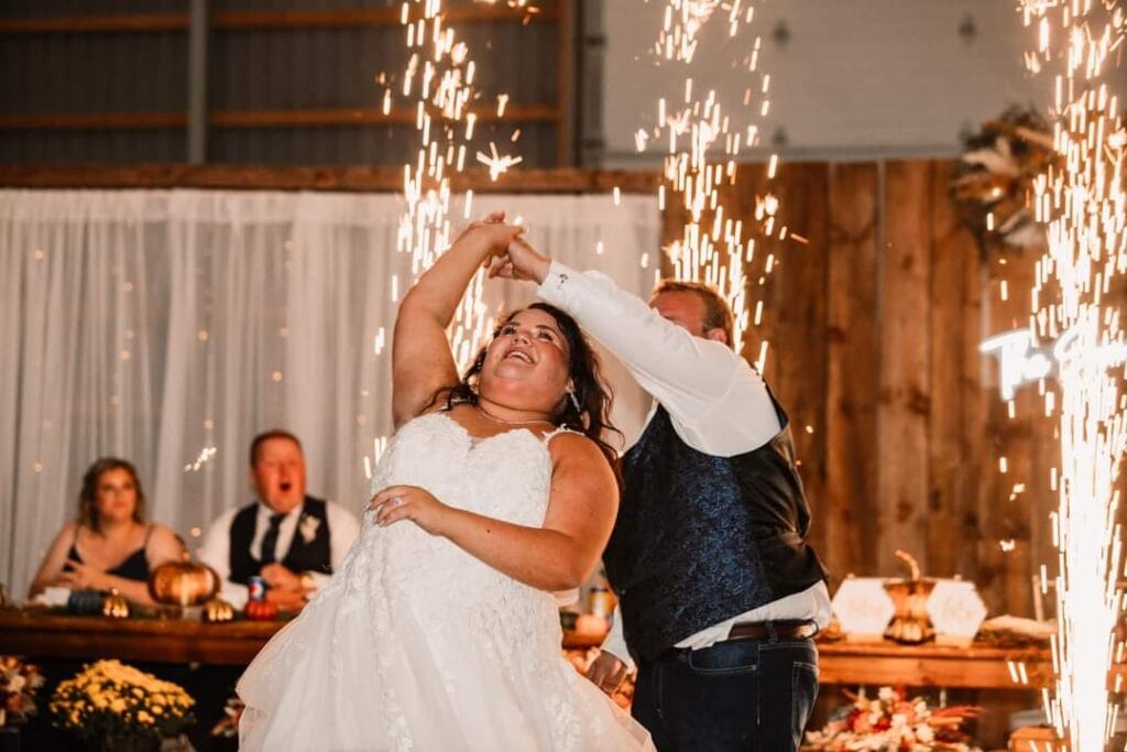 Bride and groom dancing beneath indoor cold sparks at their wedding reception