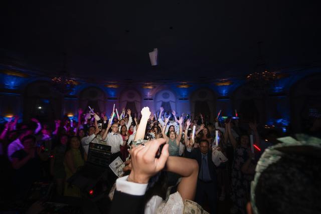 Guests celebrating on a packed dance floor during a luxury wedding reception with immersive lighting, interactive entertainment, and high-energy atmosphere.