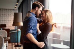Newly engaged couple sharing a romantic moment together by a window while celebrating the beginning of their wedding planning journey.