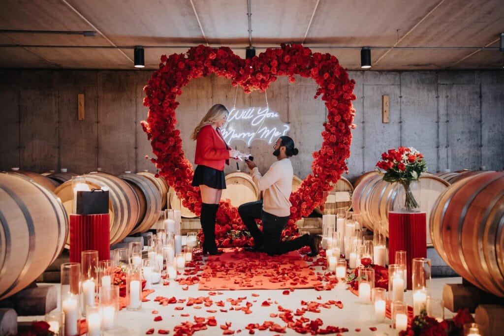 Romantic winery proposal surrounded by candlelight and red roses inside a luxury Niagara wine cellar