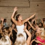 Bride celebrating on a packed dance floor surrounded by excited wedding guests during an energetic luxury wedding reception