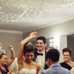 Bride and groom celebrating with guests on a packed dance floor during an elegant wedding reception