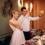 Newlywed couple smiling and raising champagne glasses during an elegant wedding reception celebration