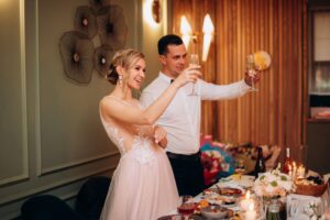 Newlywed couple smiling and raising champagne glasses during an elegant wedding reception celebration
