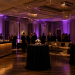 Elegant cocktail networking area with lounge seating, cocktail tables, ambient uplighting, and guests socializing at a luxury corporate event.